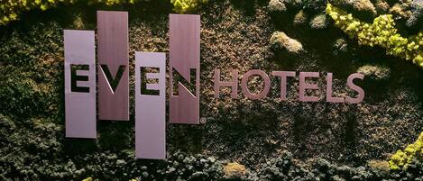 A sign with the text "EVEN HOTELS" against a backdrop of greenery and rocks.