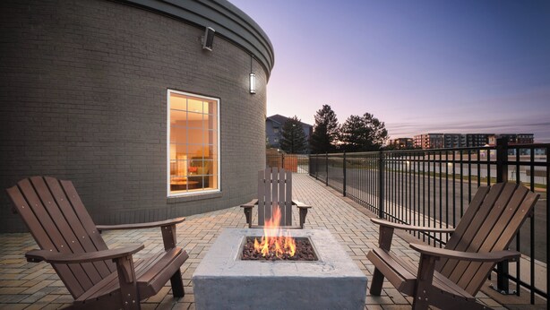 Un foyer extérieur avec deux fauteuils Adirondack sur une terrasse en briques, donnant sur le bord de l’eau.