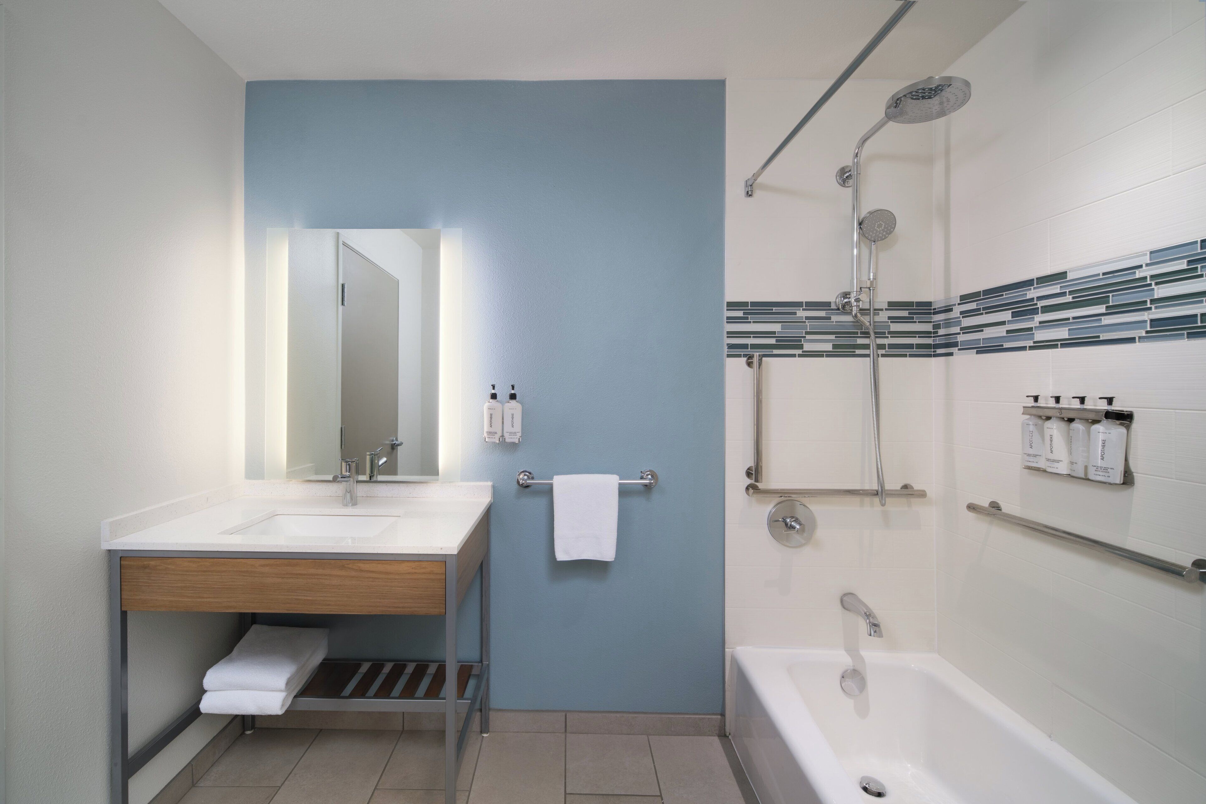 A modern bathroom with a sink, mirror, towel rack, and shower.