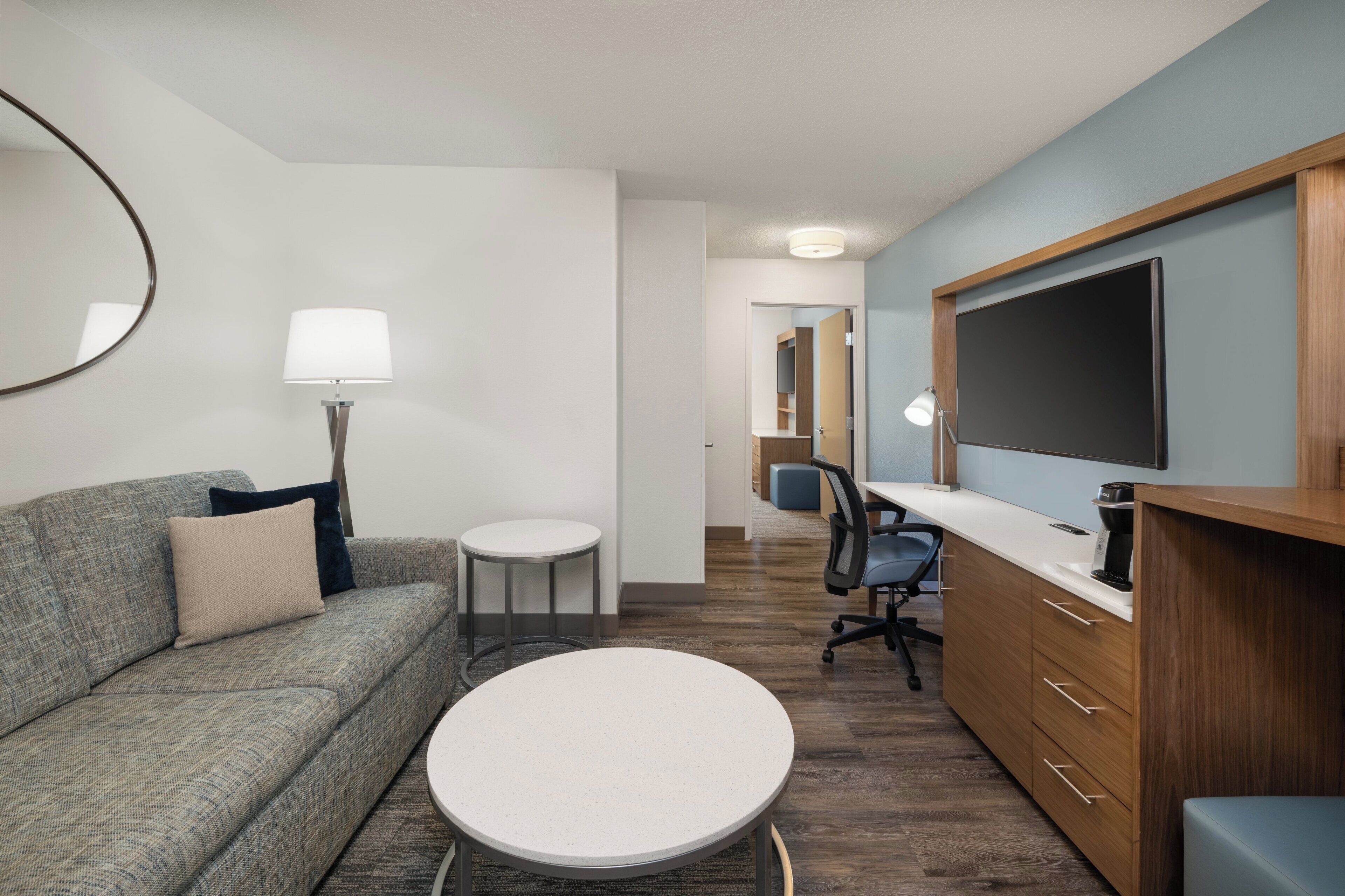 A modern room with a sofa, a round table, a desk, and a TV.