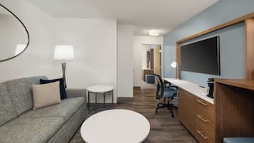 Una habitación moderna con un sofá, una mesa redonda, un escritorio y un televisor.