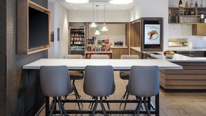 Une cuisine moderne dotée d’un îlot central, de tabourets de bar, de luminaires suspendus et d’une variété d’appareils de cuisine et de meubles de rangement.