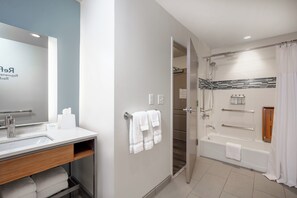 A modern bathroom with a sink, mirror, and shower area.