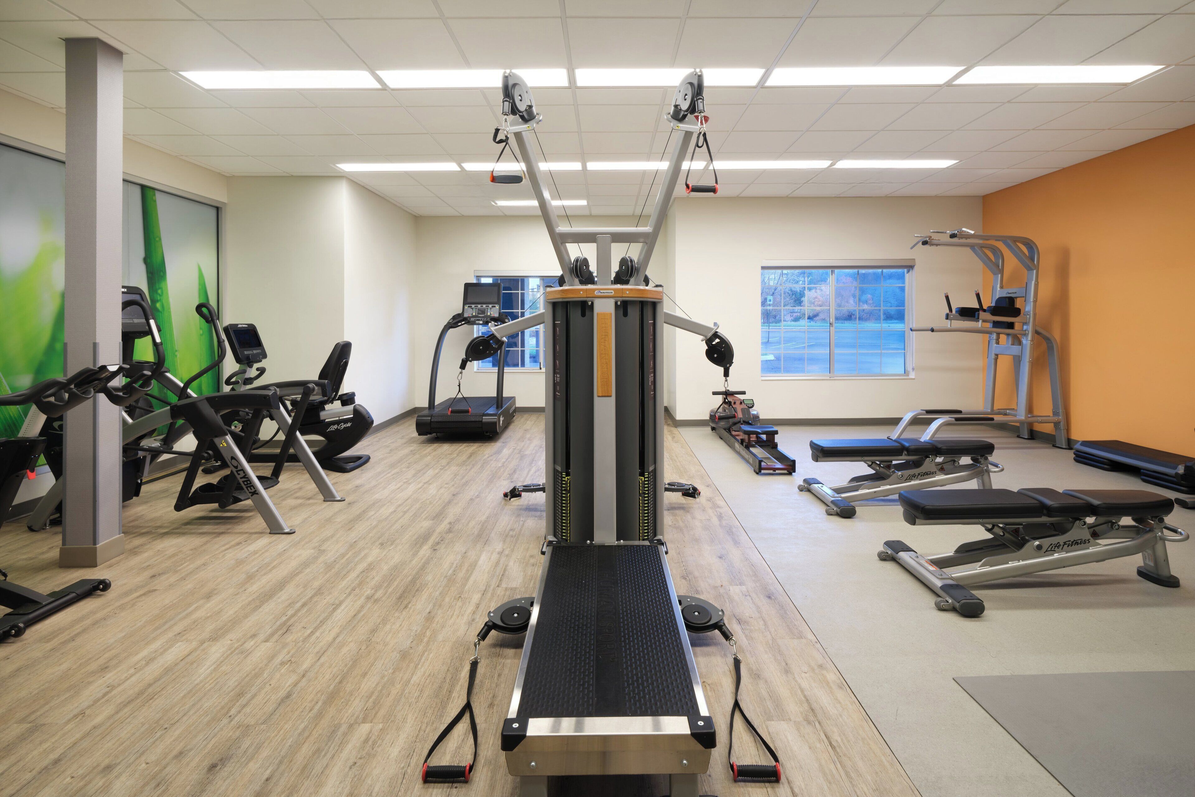 A gym with various exercise equipment including treadmills, a stationary bike, and a rowing machine.