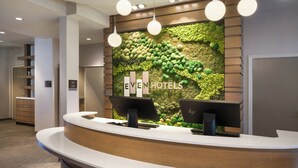 Un comptoir d’accueil d’hôtel avec un mur vert et une enseigne indiquant « EVEN HOTELS ».