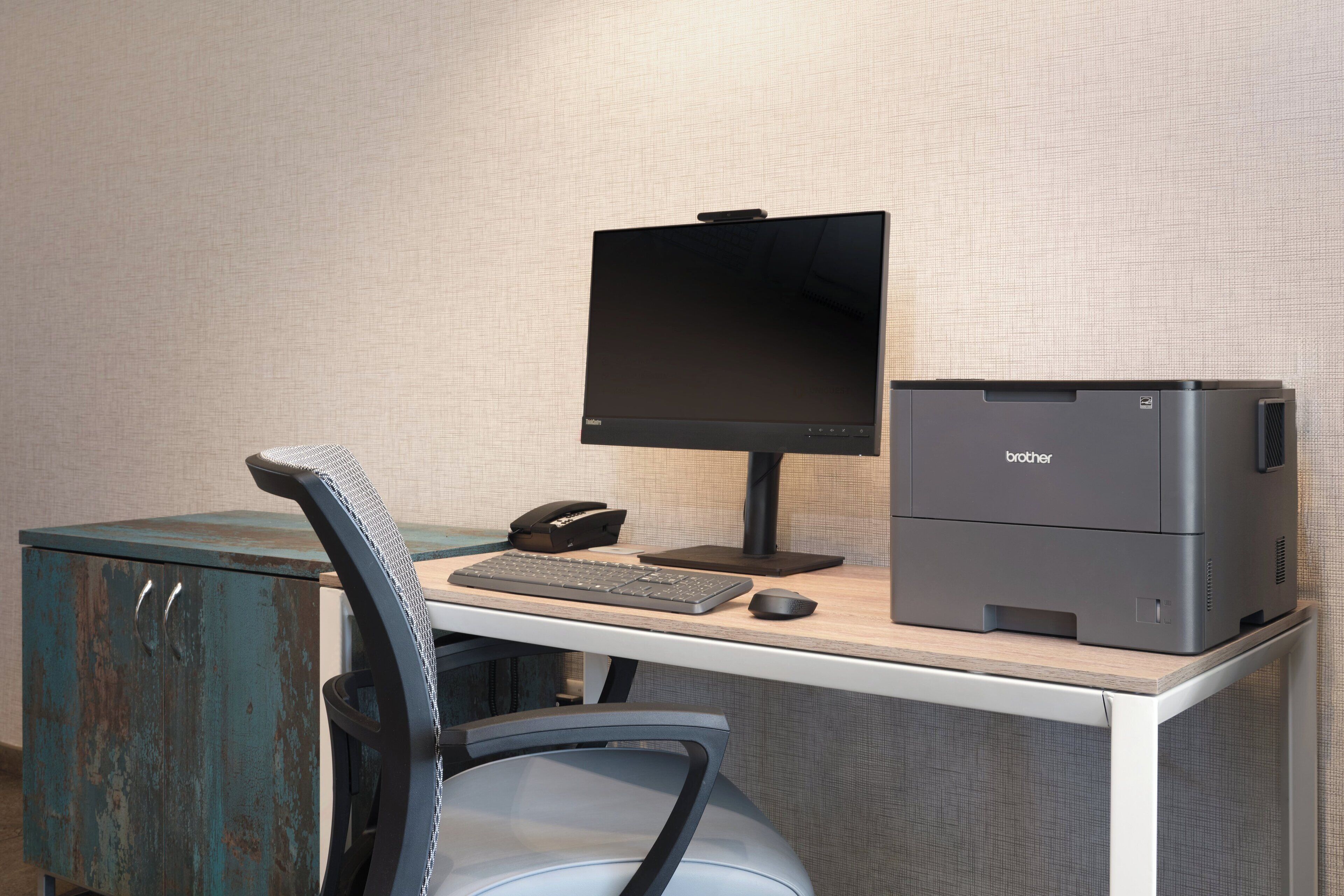 A home office setup with a desktop computer, monitor, keyboard, mouse, and printer on a desk.