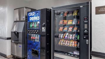 Dos máquinas expendedoras, una con el rótulo "COLD DRINKS" y la otra "ICE & VENDING", con diferentes aperitivos y bebidas en su interior.