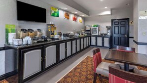 A hotel kitchen with a long counter, coffee machines, and a refrigerator.