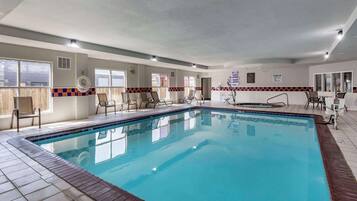 Relax by the pool with lounge chairs and a small table nearby.