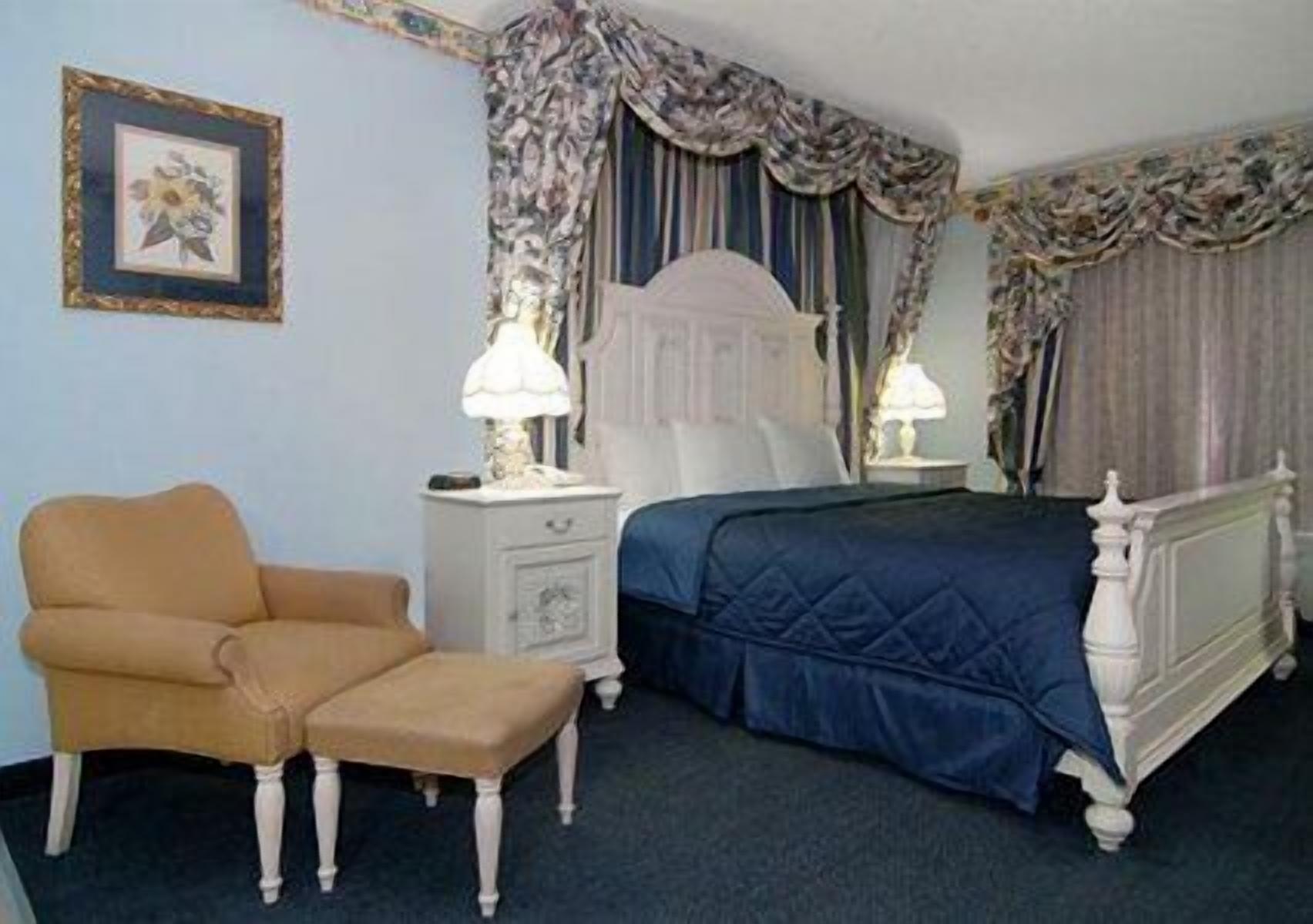 A bedroom with a bed, a nightstand, a chair, and a picture on the wall.