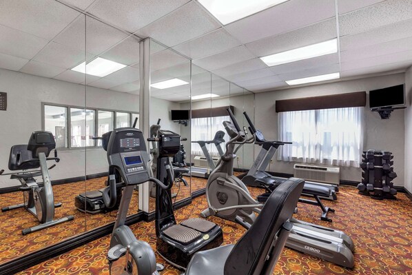 Un gimnasio con cintas de correr, máquinas elípticas y equipo de pesas.