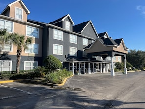 A multi-story hotel with a covered entrance and a parking lot.