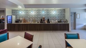 A modern hotel lobby with a central counter, seating area, and a coffee machine. - La Quinta Inn & Suites by Wyndham Rockwall (Rockwall)