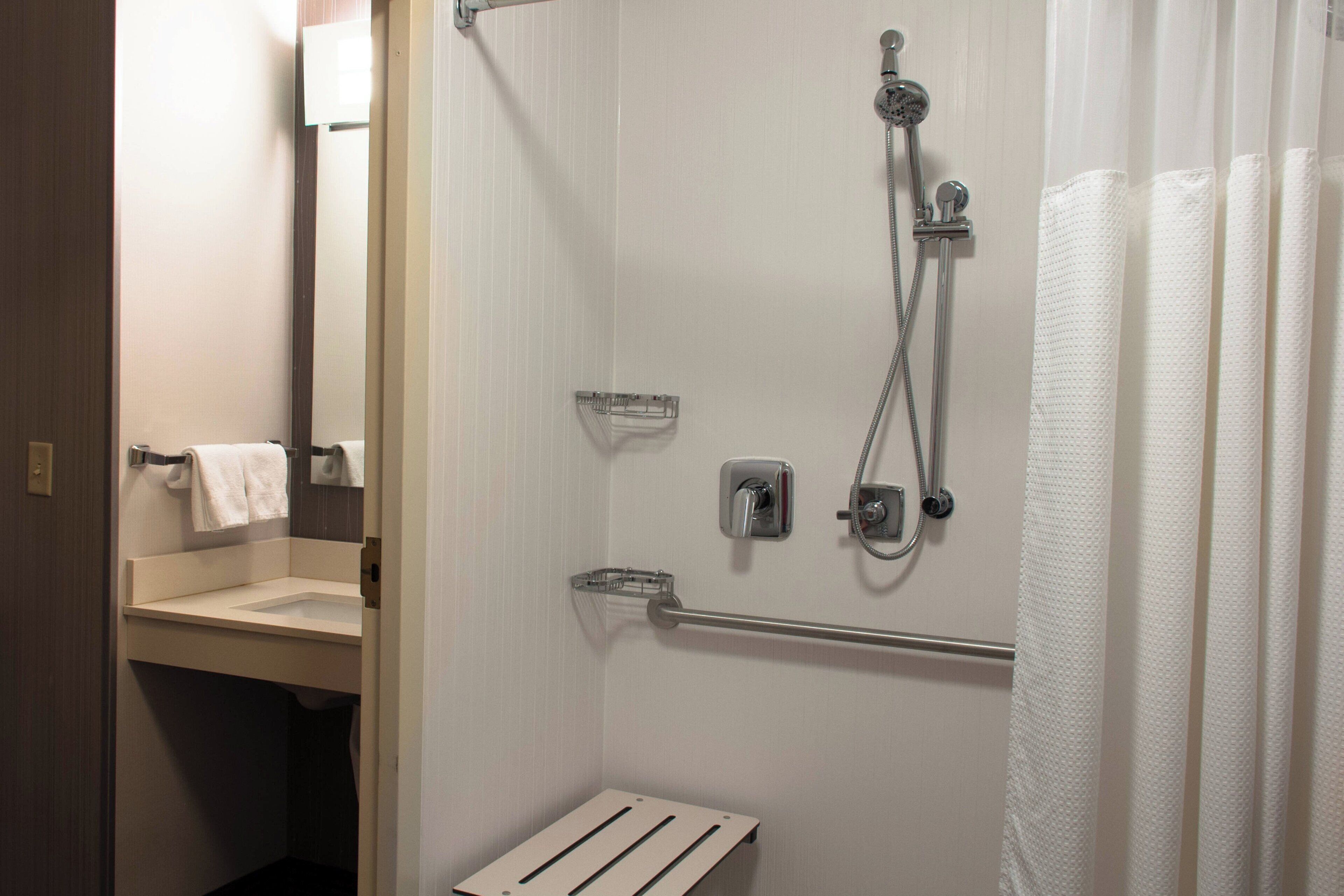 A bathroom with a shower, a sink, and a towel rack.