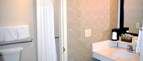 A bathroom with a toilet, a shower curtain, a sink with a mirror, and a towel rack.