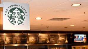 Ein Starbucks-Schild mit dem Text 'Wir servieren stolz' und einem Logo.