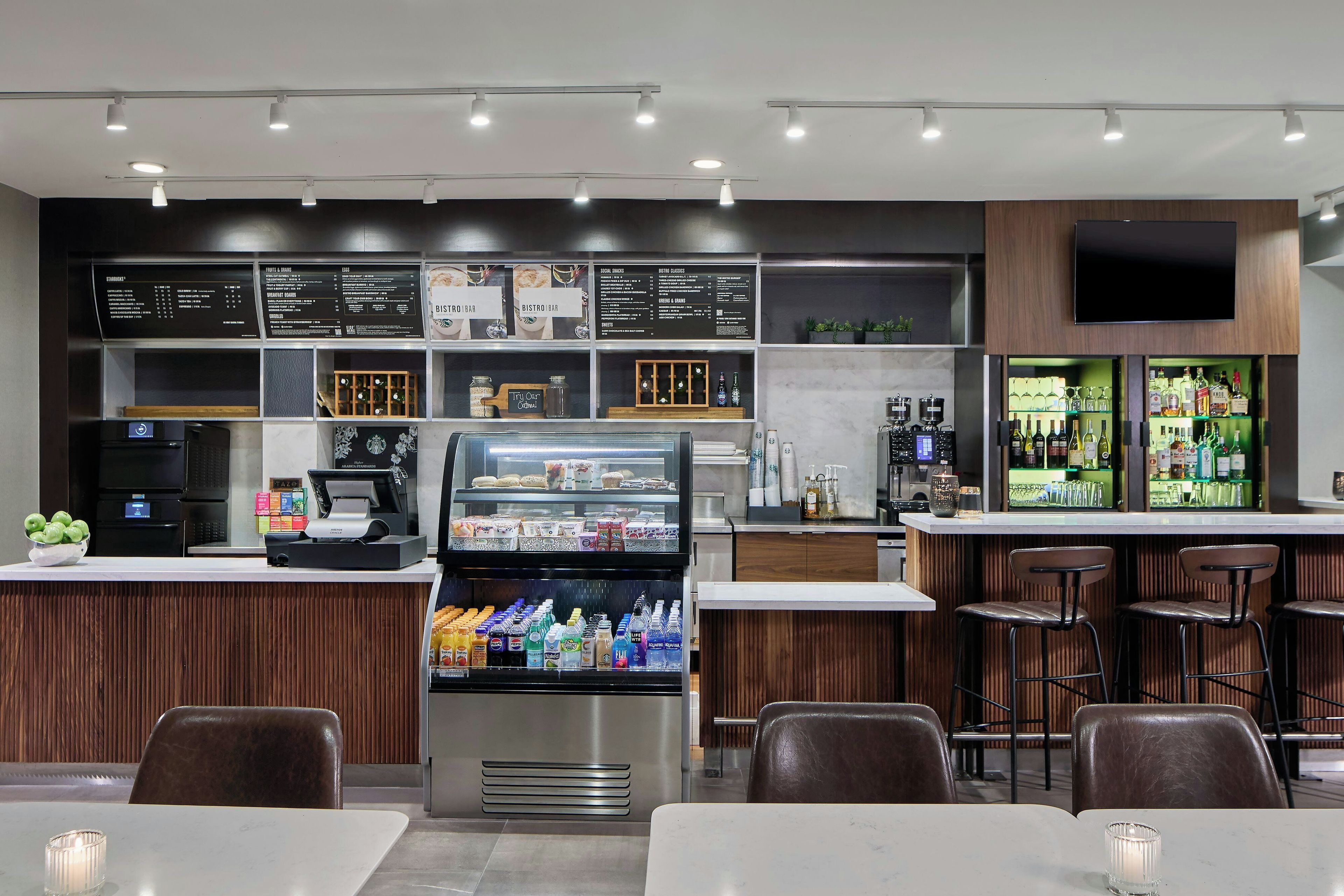 A modern cafe with a coffee machine, a refrigerated drink display, and a menu board.