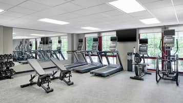 A gym with treadmills, weight machines, and dumbbells.
