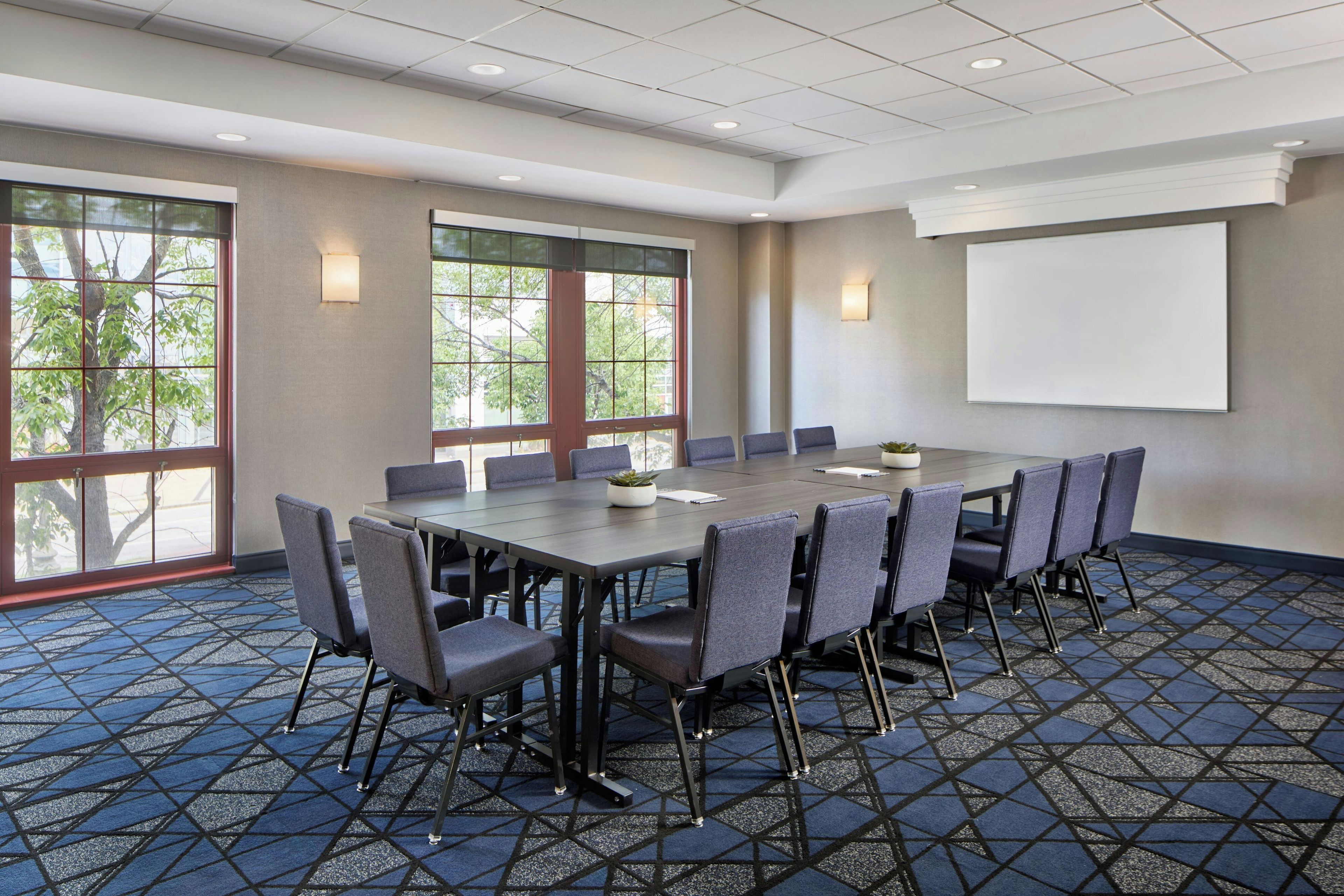 A conference room with a large table, chairs, and a projector screen.
