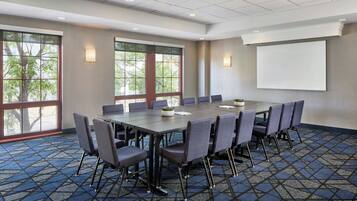 A conference room with a large table, chairs, and a projector screen.