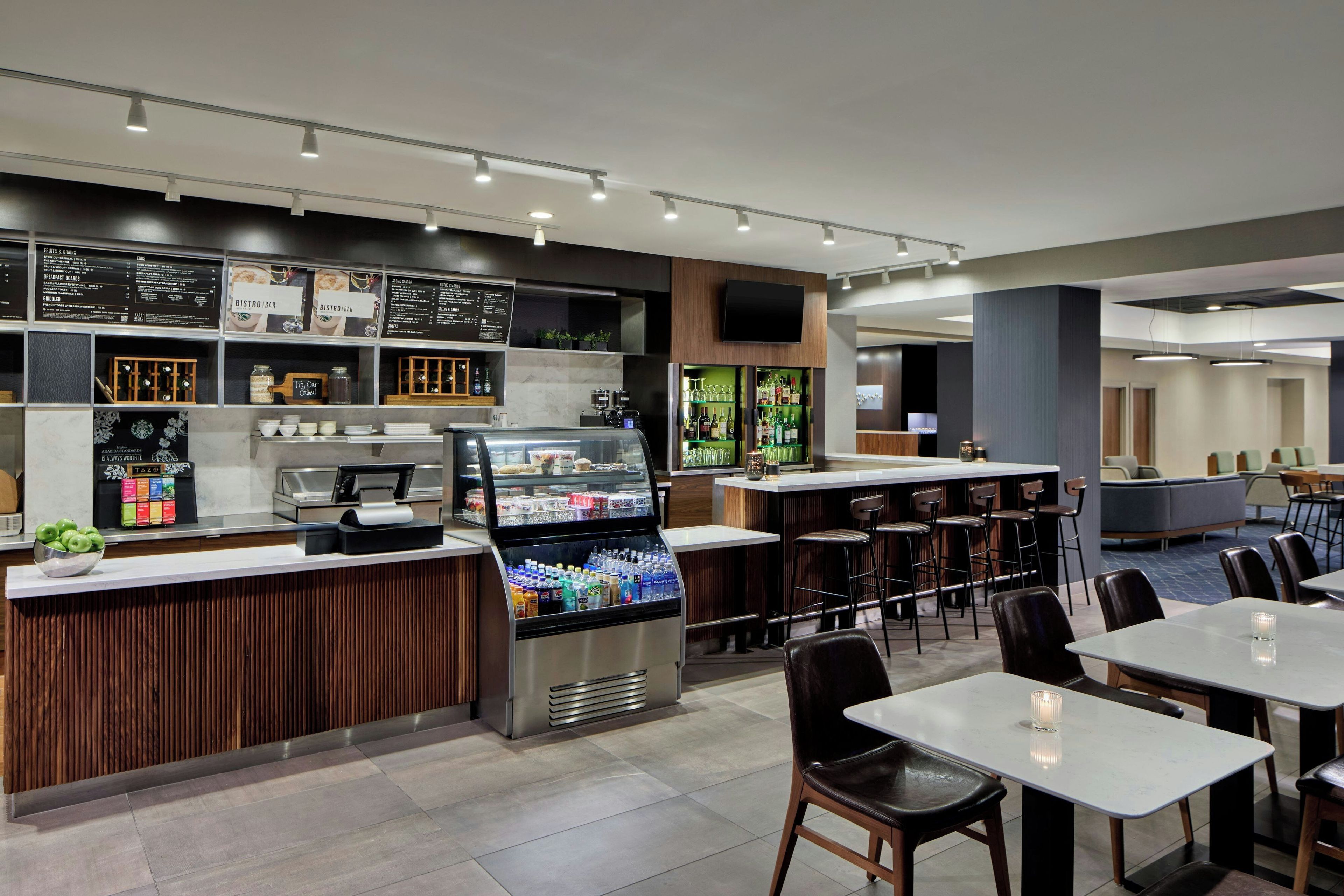 A modern cafe with a self-service counter, seating area, and a variety of food and drink options.