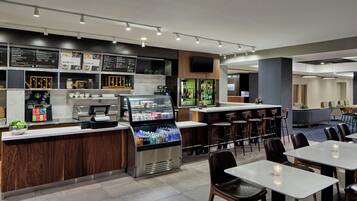 A modern cafe with a self-service counter, seating area, and a variety of food and drink options.