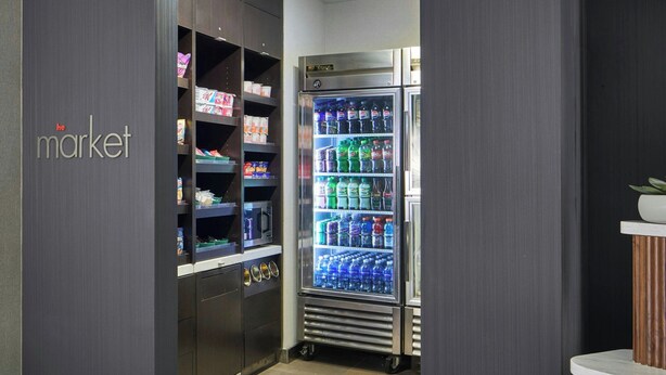 A modern interior with a vending machine, a 'market' sign, and a wooden counter. - Courtyard by Marriott Providence Downtown (Providence)