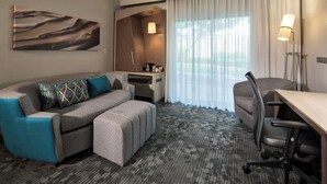 Een hotelkamer met een bank, een bureau, een stoel, een lamp en een schilderij aan de muur.