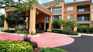 Een Courtyard Marriott hotel met een rode bakstenen entree, meerdere balkons en aangelegde tuinen.