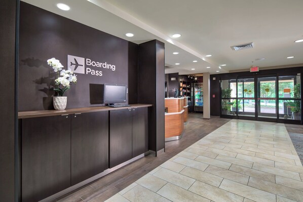 A modern reception area with a 'Boarding Pass' sign, a reception desk, and a view of the outside through glass doors.