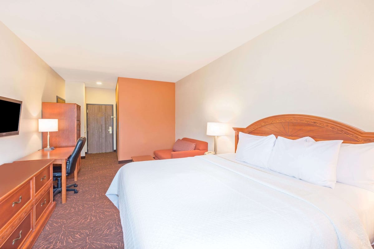 Una habitación de hotel con cama, escritorio, silla y televisor.
