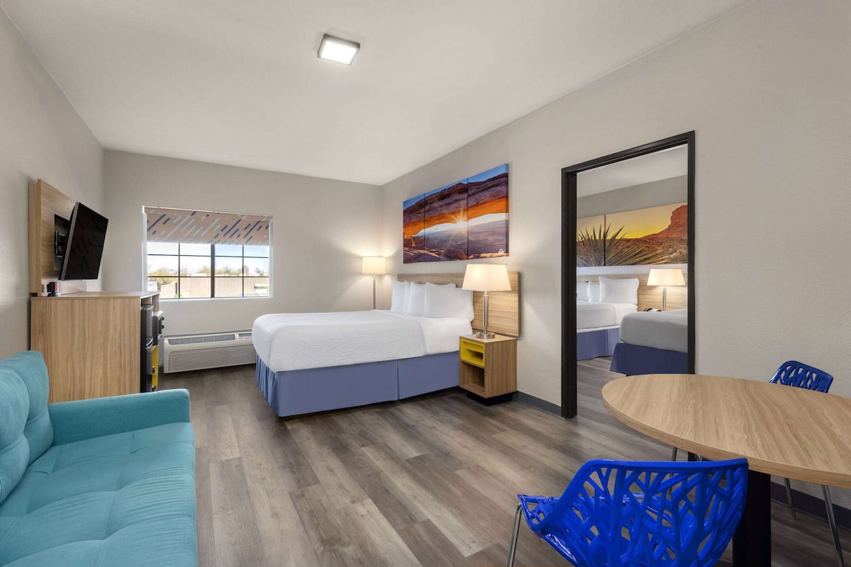 Una habitación de hotel con cama, escritorio, silla, mesa y televisor.