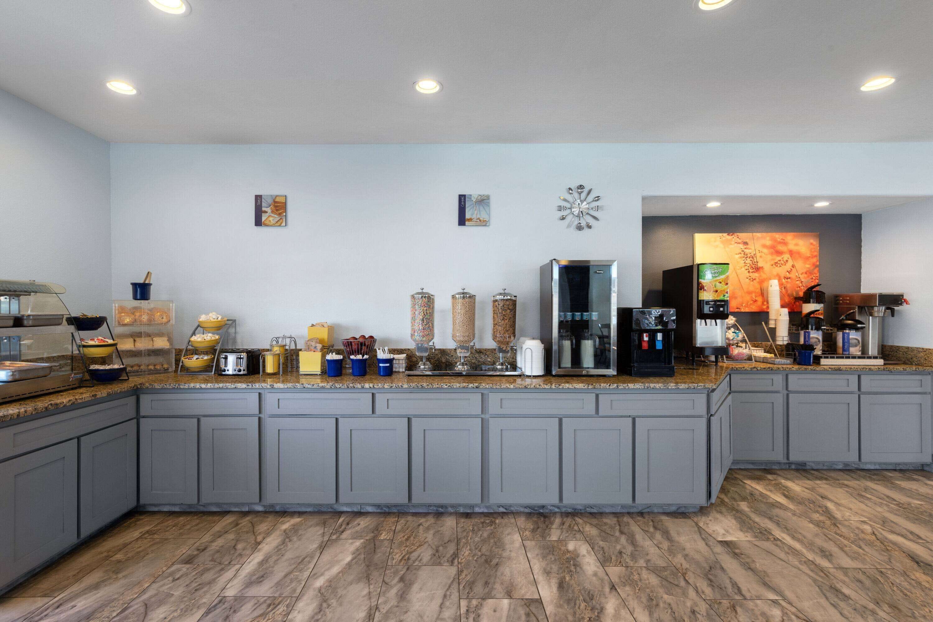 A modern kitchen with grey cabinets, a marble countertop, and various appliances and utensils.