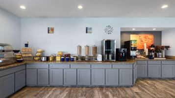 A modern kitchen with grey cabinets, a marble countertop, and various appliances and utensils.