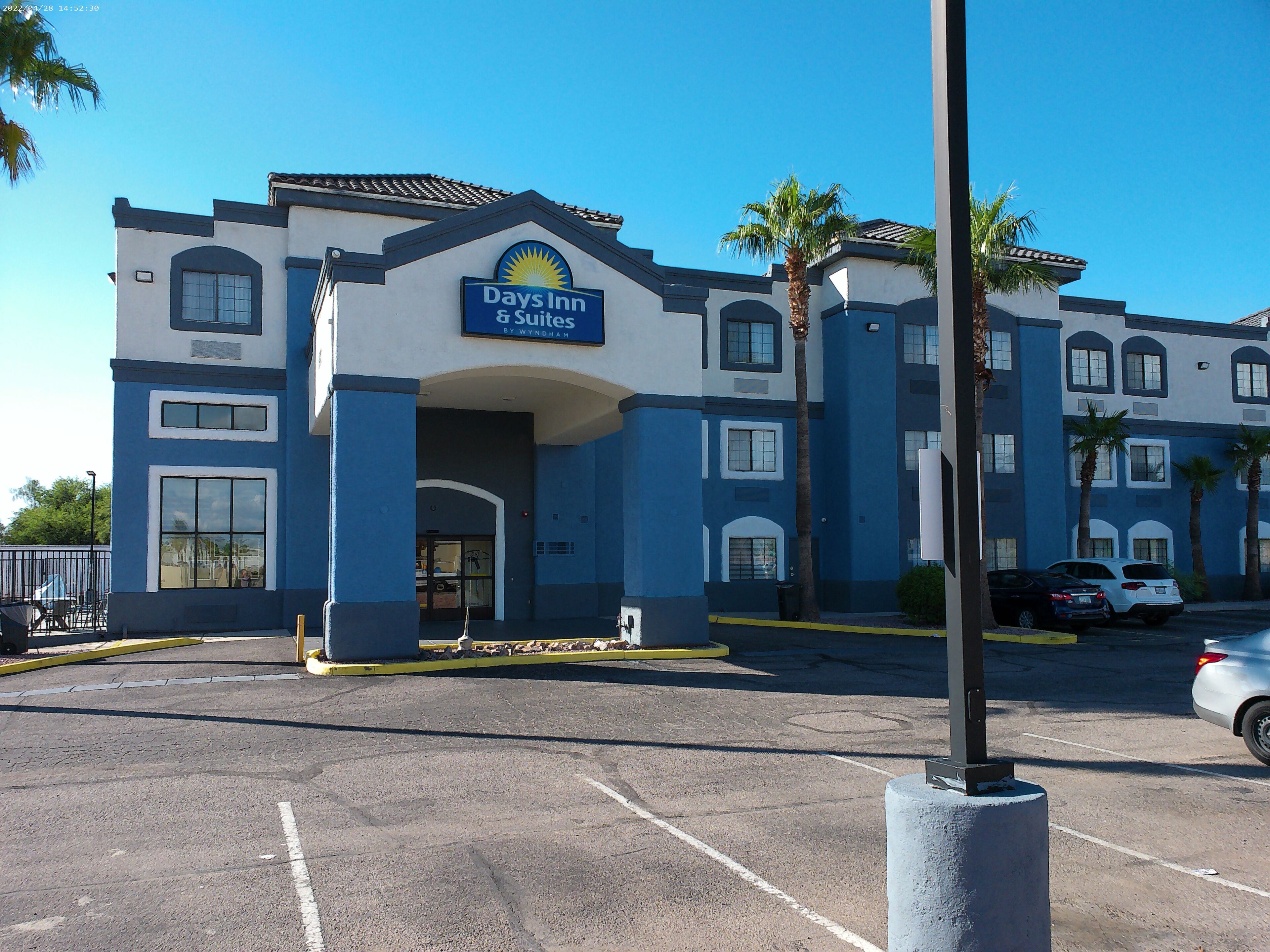 Edifício Days Inn & Suites com entrada visível, estacionamento e palmeiras.