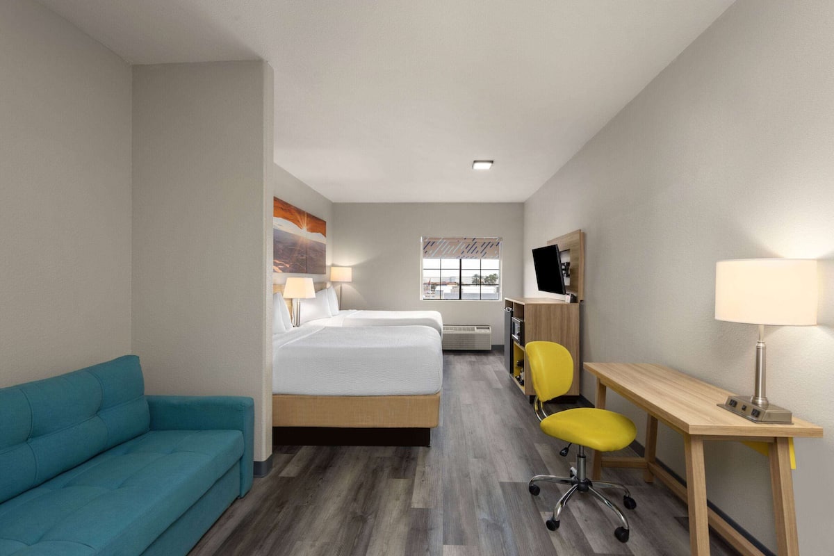 Habitación de hotel con cama, escritorio, silla, sofá y televisión.