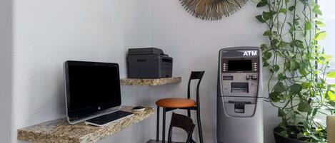Un'area dedicata al lavoro, con un portatile, una stampante, un bancomat e una sedia.