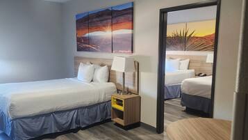 Een hotelkamer met twee bedden, een kleine tafel, een stoel, een nachtkastje en een schilderij aan de muur.