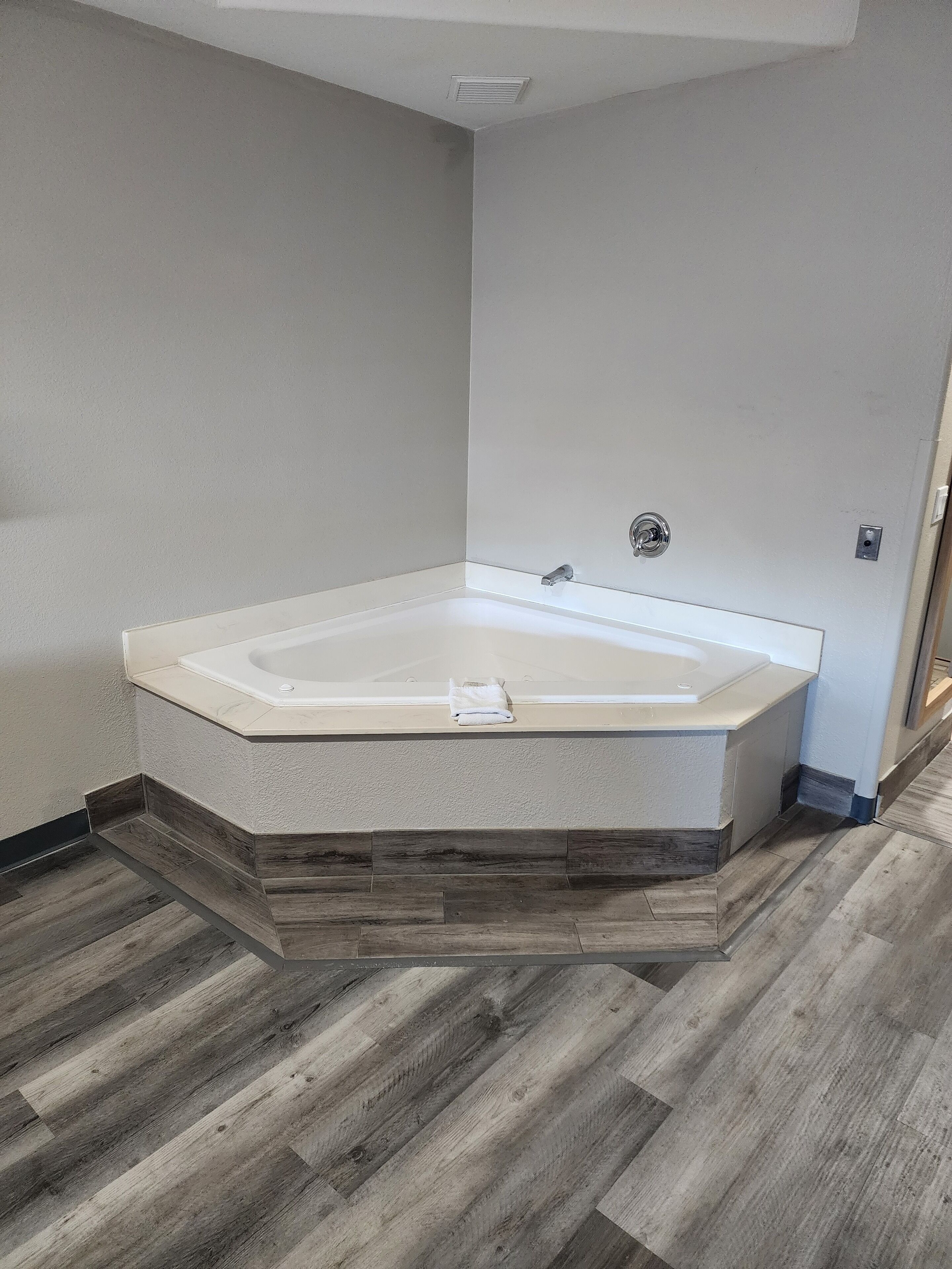 A modern bathroom with a freestanding bathtub, wooden flooring, and a neutral color scheme.