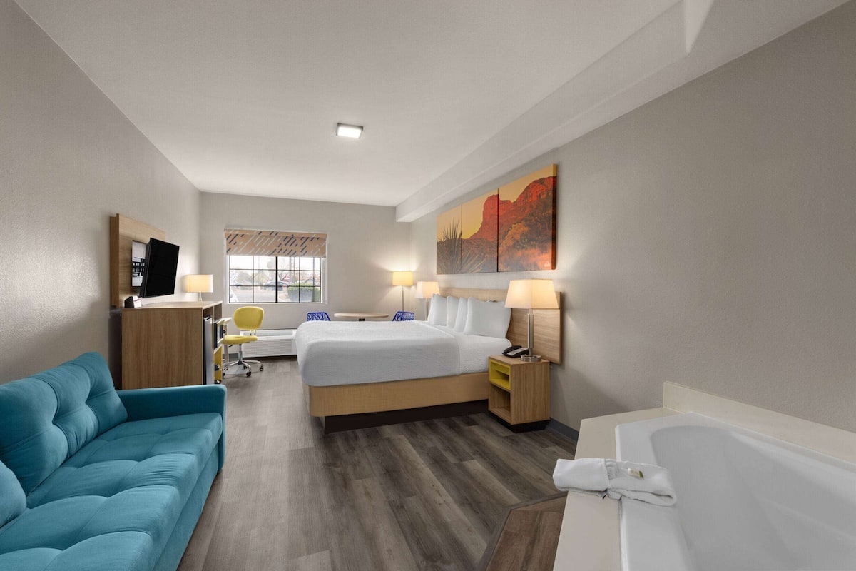 Una habitación de hotel con cama, sofá, escritorio y baño.