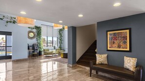 Un hall con un banco, una escalera y un mostrador de recepción.