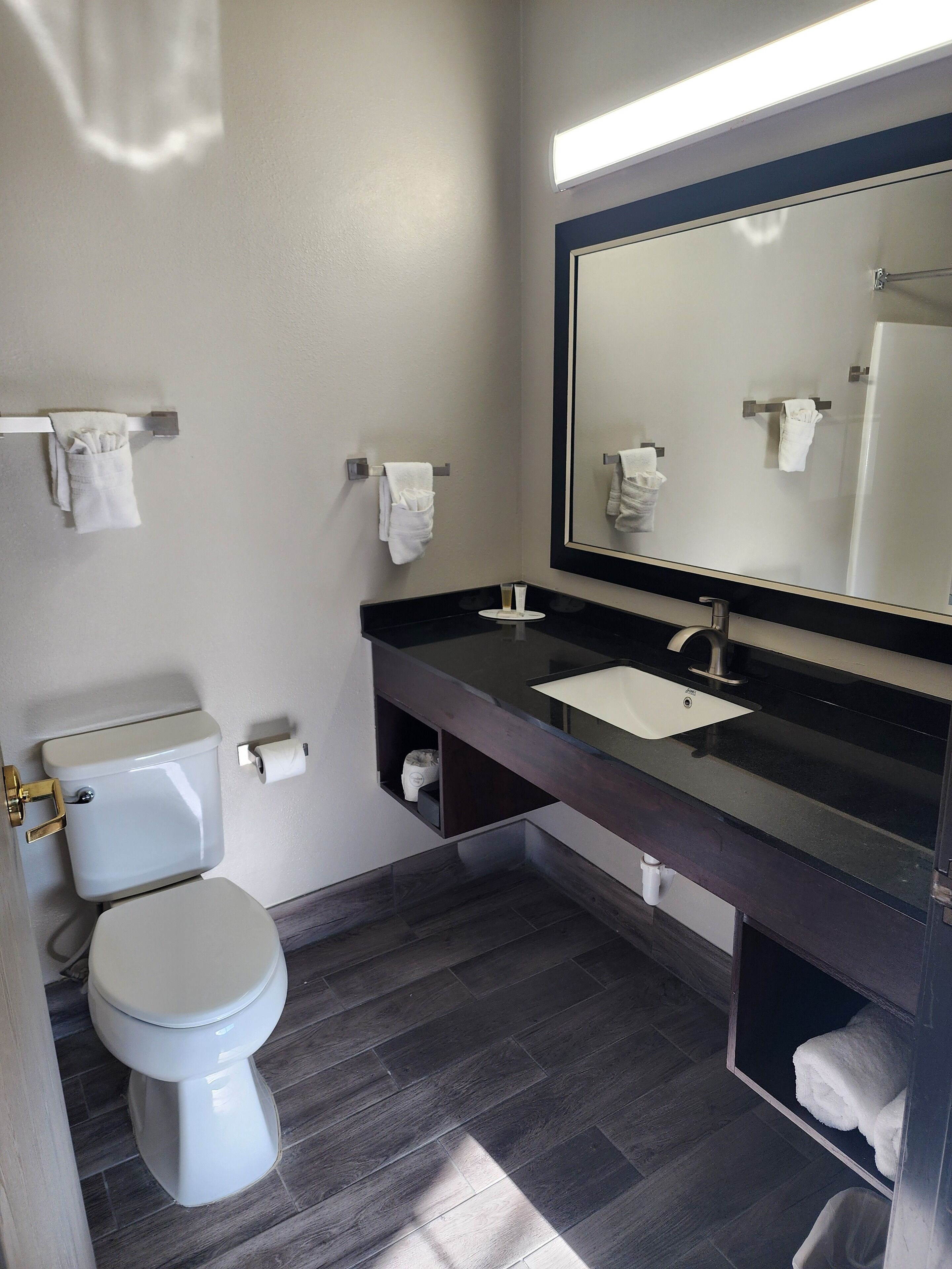 Un baño moderno con inodoro, lavamanos y un espejo grande.