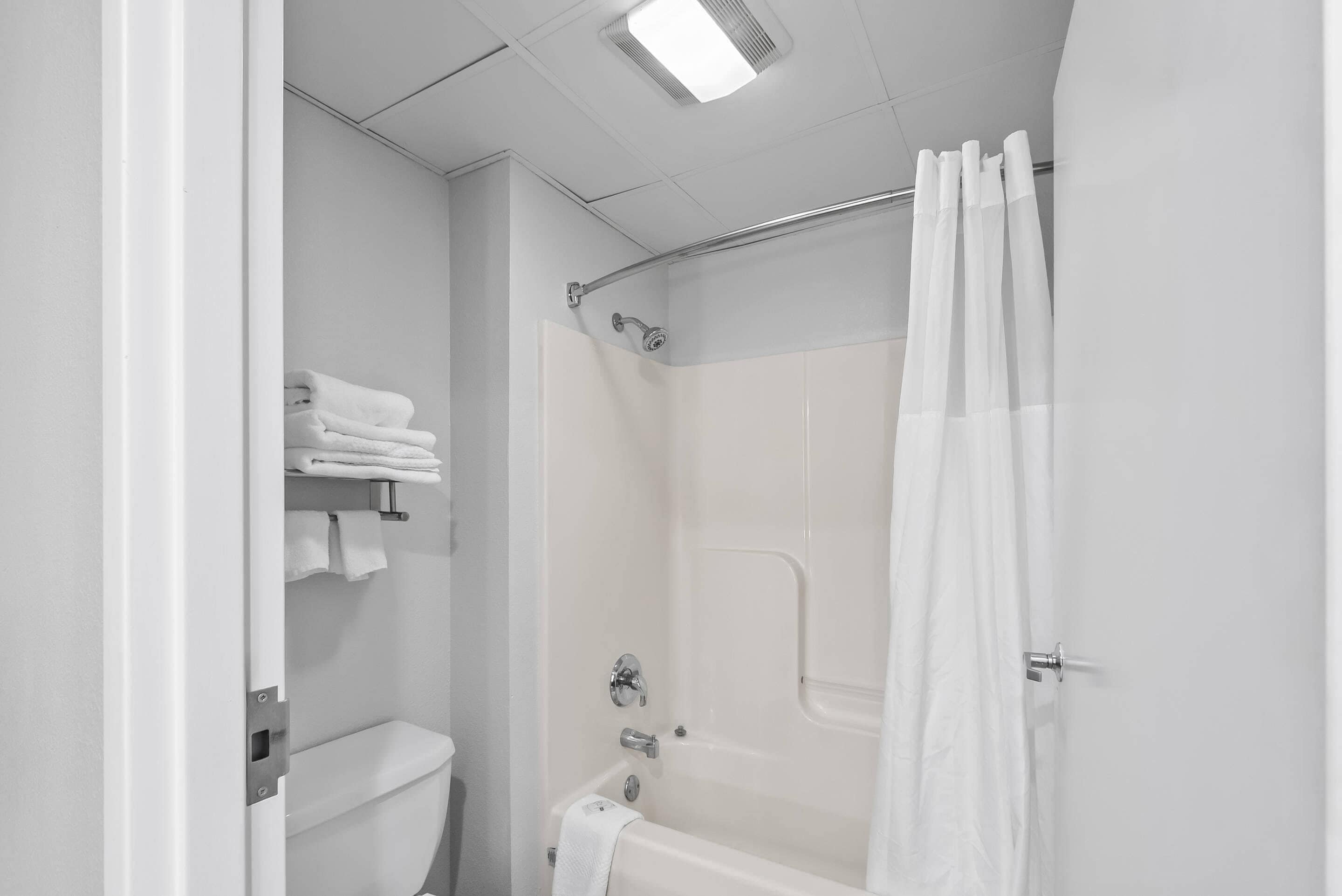 A white bathroom with a shower curtain, a toilet, and a towel rack.