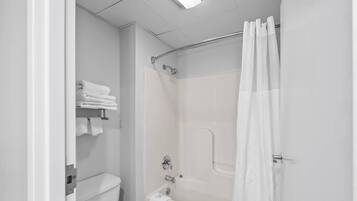A white bathroom with a shower curtain, a toilet, and a towel rack.