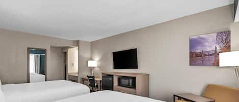 Quarto de hotel com duas camas, uma escrivaninha com computador, televisão e uma pequena mesa.