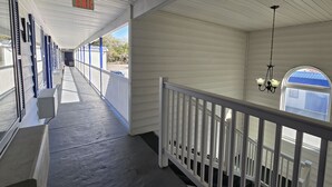 A covered corridor with a white railing, a hanging light fixture, and a view of the outside. - OYO Hampton South Carolina Hwy 278 (Hampton)