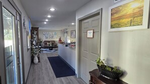 A hallway with a wooden floor, a reception desk, a couch, and a door marked 'Employees Only'. - OYO Hampton South Carolina Hwy 278 (Hampton)