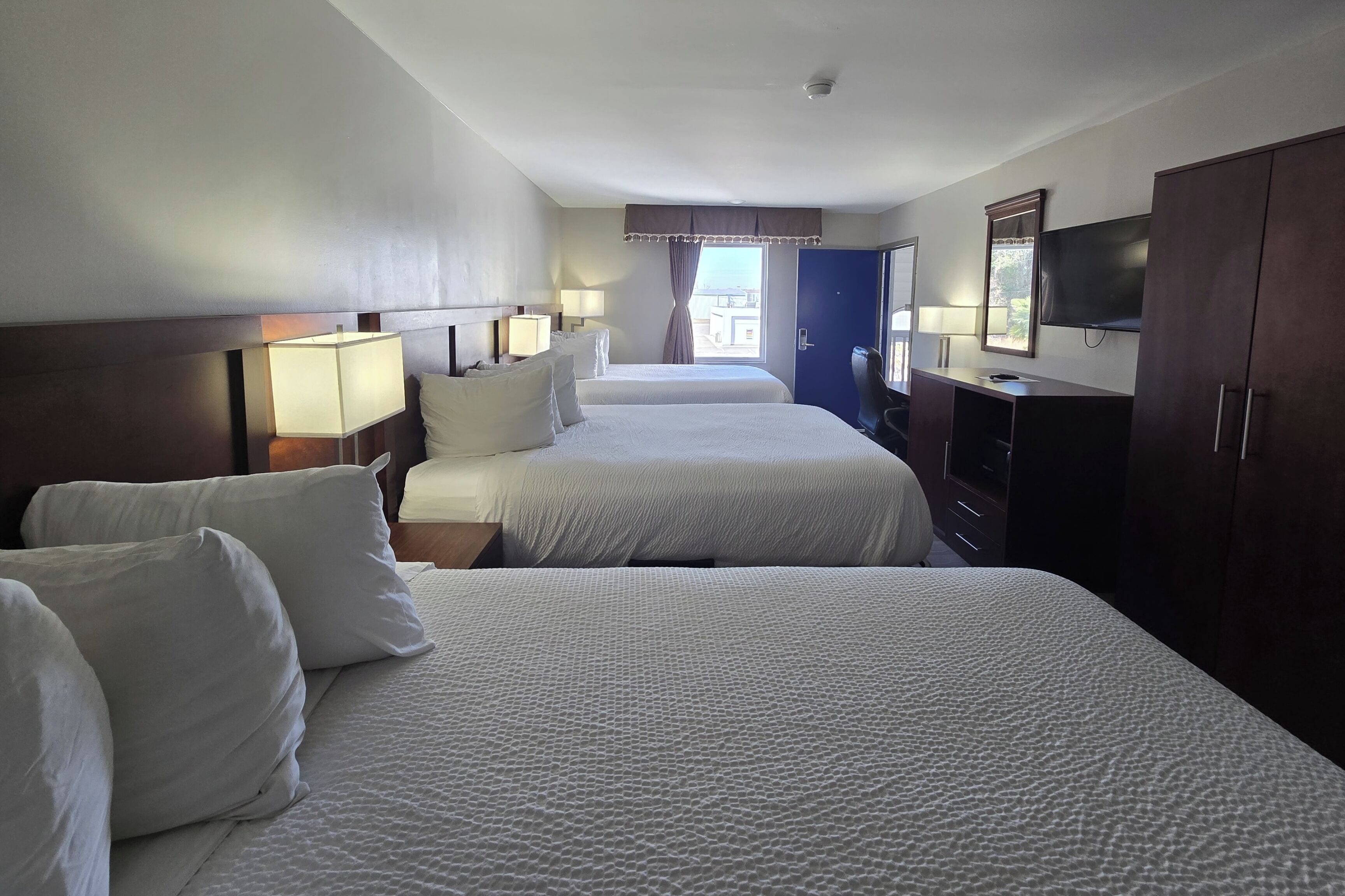 A hotel room with two beds, a TV, a desk, and a wardrobe.