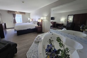 Quarto de hotel com cama, mesas de cabeceira, espelho grande, banheira, sofá e televisão.