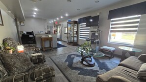 A modern living room with a stone-patterned sofa, a glass coffee table, and a dining area with a wooden table and chairs. - OYO Hampton South Carolina Hwy 278 (Hampton)